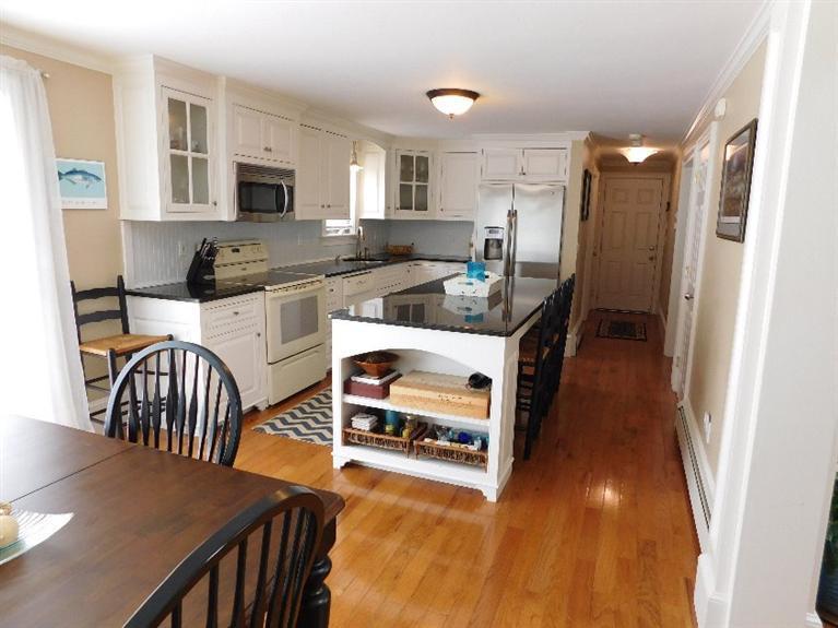 62 Quisset Road Centerville, MA 02632 - Photo 8 of 25 a kitchen with stainless steel appliances granite countertop a refrigerator a stove top oven a sink dishwasher and white cabinets with wooden floor