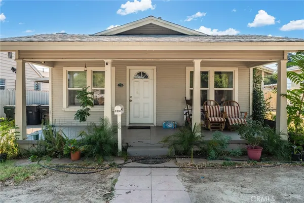 a view of a house with potted plants and a table and chairs in patio
