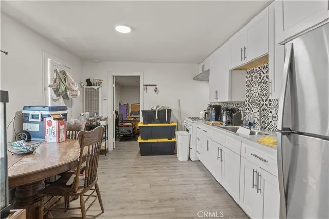 a kitchen with stainless steel appliances a refrigerator a stove a sink dishwasher and white cabinets with wooden floor