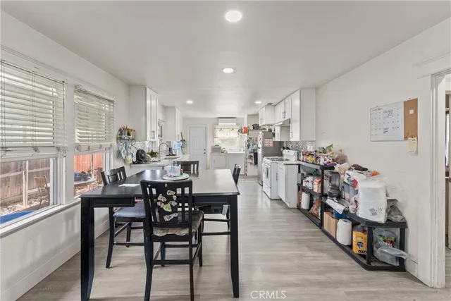 a dining room with stainless steel appliances kitchen island granite countertop a dining table chairs and a white refrigerator with a large window
