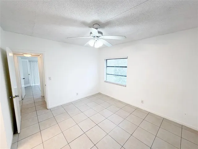 an empty room with windows and ceiling fan