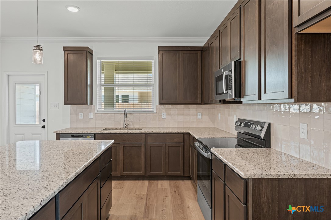 7810 Timber Holw Lane Temple, TX 76502 - Photo 15 of 32 a kitchen with a sink dishwasher a stove top oven a refrigerator with wooden cabinets