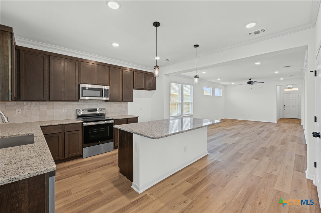 7810 Timber Holw Lane Temple, TX 76502 - Photo 17 of 32 a kitchen with kitchen island granite countertop wooden floors and stainless steel appliances