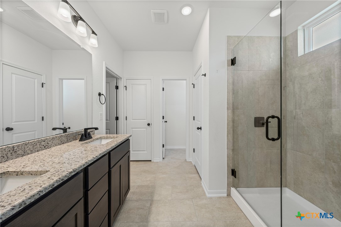 7810 Timber Holw Lane Temple, TX 76502 - Photo 27 of 32 a bathroom with a granite countertop sink a mirror a bathtub and shower