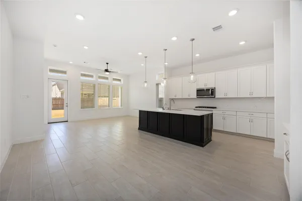 a large kitchen with stainless steel appliances kitchen island granite countertop a large counter top and a stove top oven