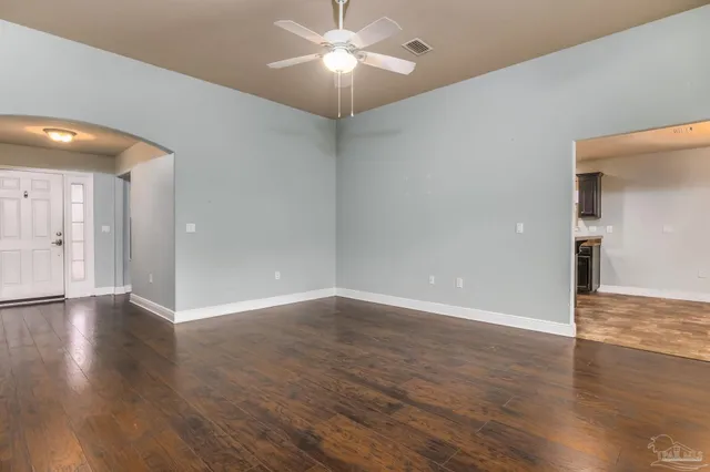 a view of an empty room with window and wooden floor