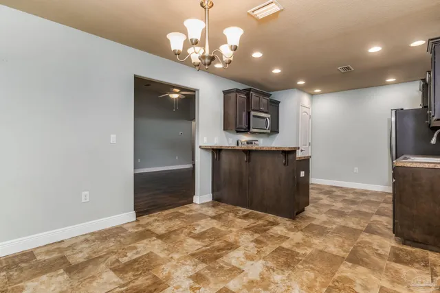 a kitchen with kitchen island granite countertop a refrigerator and a sink