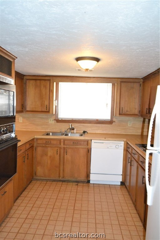 a kitchen with a sink a stove top oven and cabinetry