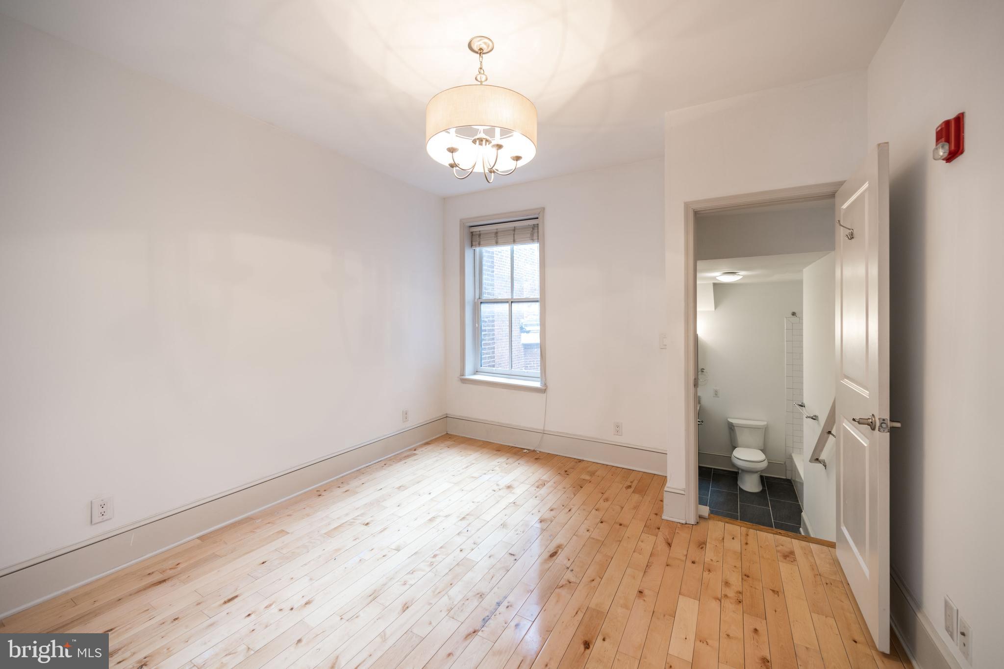 1310 Spruce Street, Unit 301 Philadelphia, PA 19107 - Photo 6 of 11 an empty room with wooden floor and a bathroom