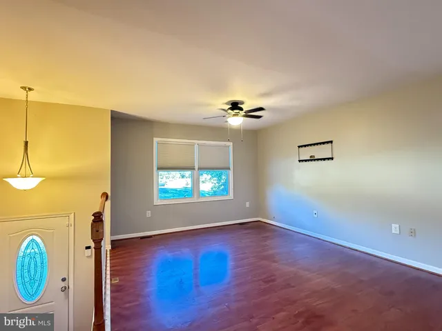 an empty room with wooden floor fan and windows