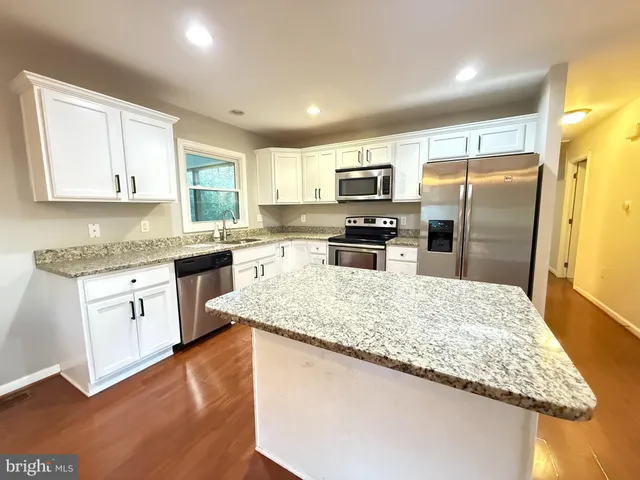 a kitchen with kitchen island granite countertop stainless steel appliances stove a sink and a refrigerator