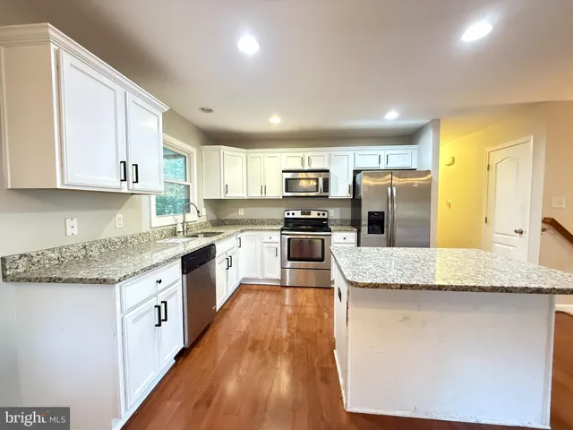 a large kitchen with granite countertop a white stove top oven and cabinets
