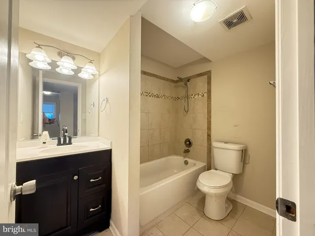 a bathroom with a bathtub shower sink mirror vanity and toilet