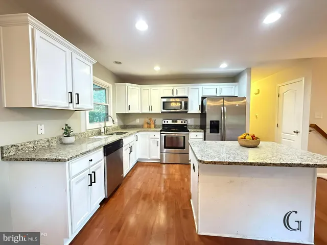 a large kitchen with granite countertop a sink and cabinets with wooden floor