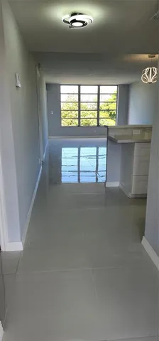 an empty room with windows and view of kitchen