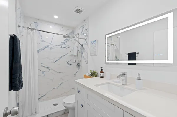 a bathroom with a sink vanity granite toilet and shower