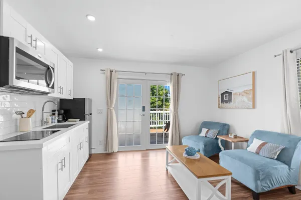 a living room with stainless steel appliances furniture a rug and a kitchen view