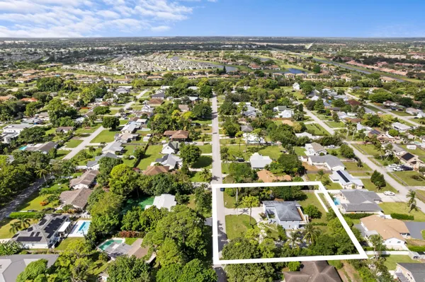 an aerial view of residential houses with outdoor space and trees