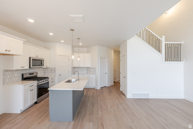 5228 South Acacia Drive, Unit 808 Mapleton, UT 84664 - Photo 13 of 22 Open concept kitchen featuring white cabinetry, a large island with sink, stainless steel appliances, and a tiled backsplash