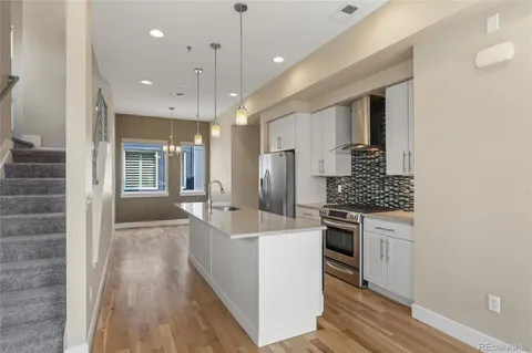 a kitchen with stainless steel appliances a refrigerator sink and wooden floor