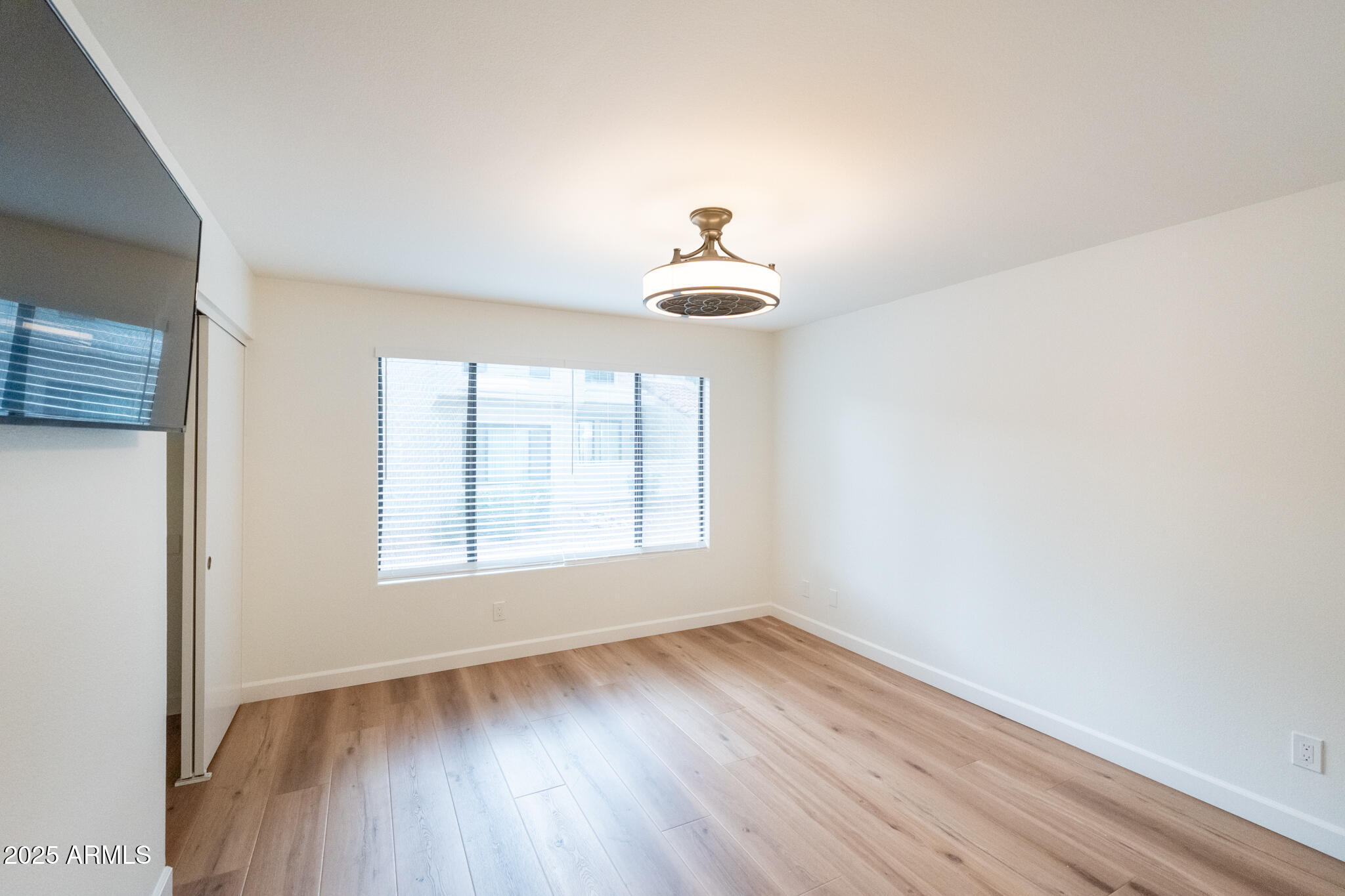 10115 East Mountain View Road, Unit 1089 Scottsdale, AZ 85258 - Photo 12 of 28 an empty room with wooden floor a ceiling fan and windows