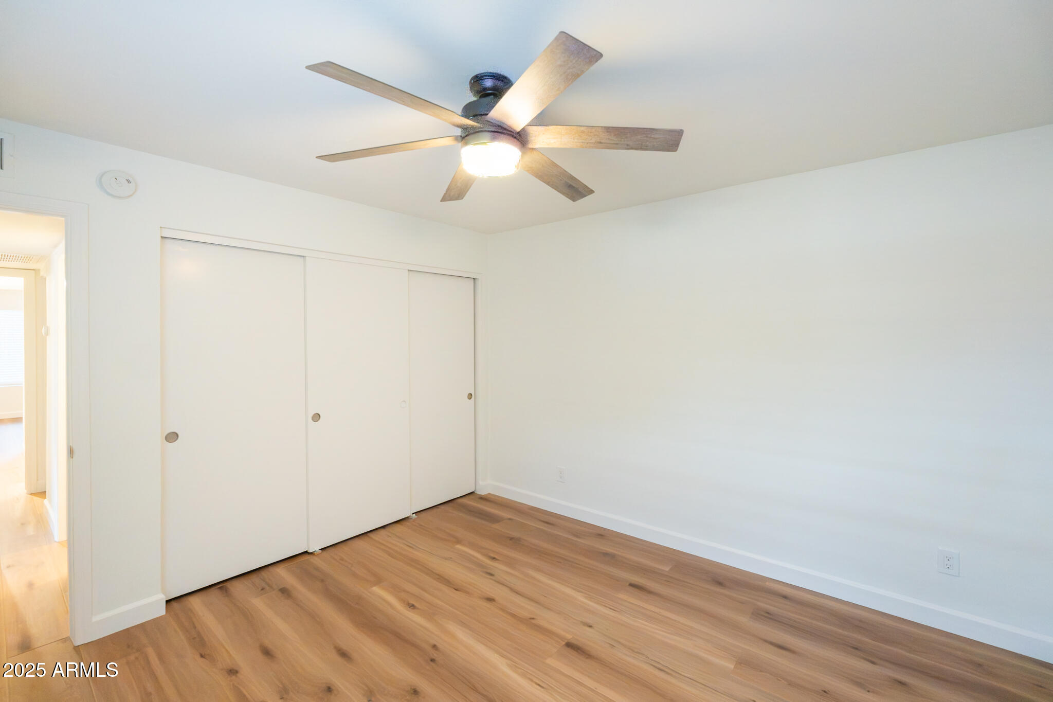 10115 East Mountain View Road, Unit 1089 Scottsdale, AZ 85258 - Photo 19 of 28 an empty room with wooden floor and fan