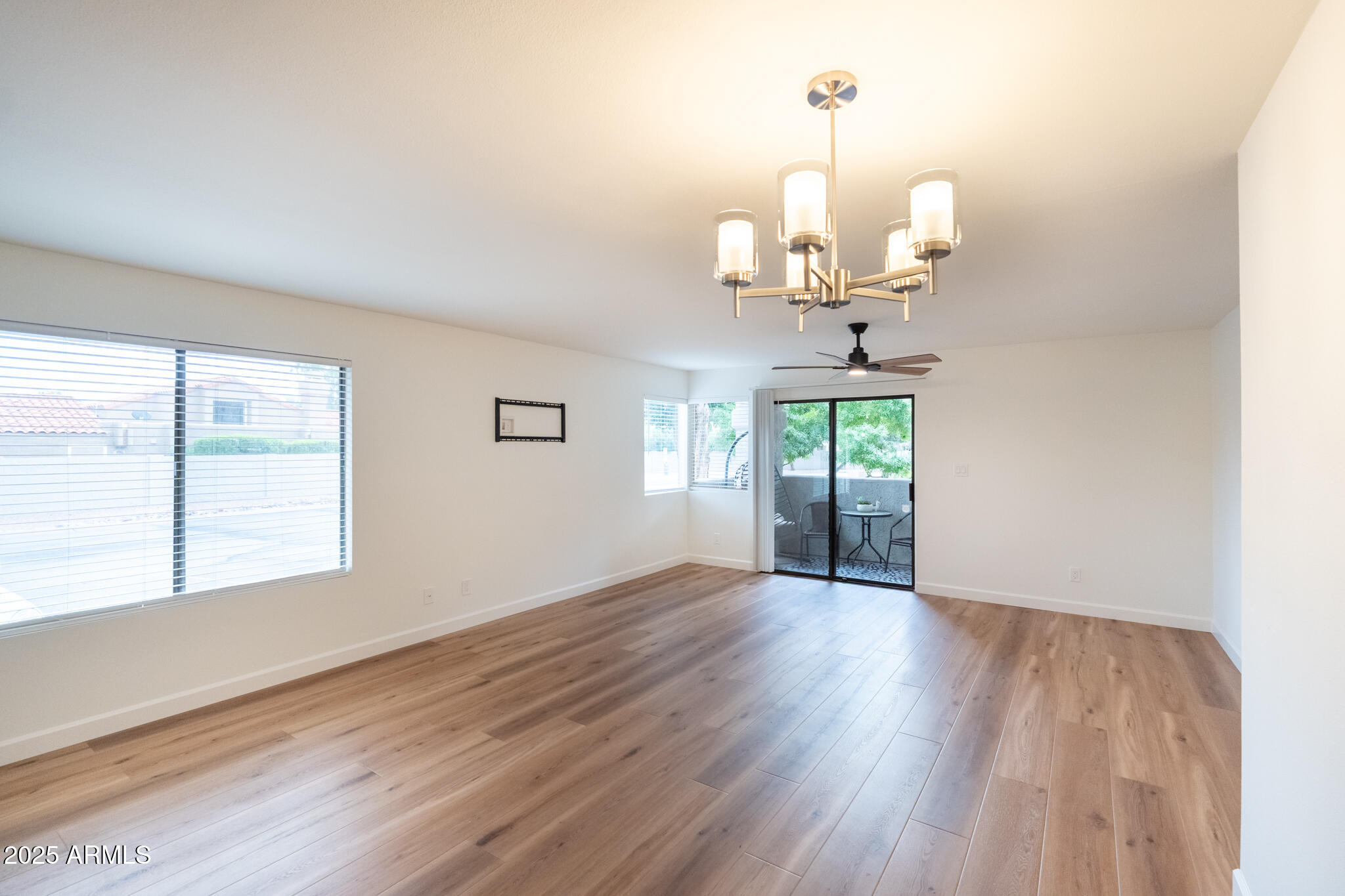 10115 East Mountain View Road, Unit 1089 Scottsdale, AZ 85258 - Photo 5 of 28 an empty room with wooden floor chandelier and windows