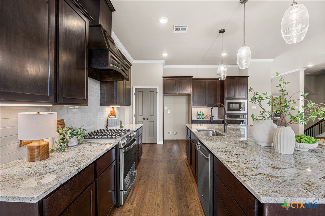 2136 Oak Draw Court Belton, TX 76513 - Photo 7 of 46 a kitchen with granite countertop stainless steel appliances a sink a counter space cabinets and wooden floor