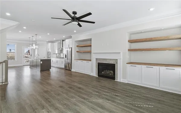 a view of a livingroom with a kitchen hardwood floor a ceiling fan and kitchen view