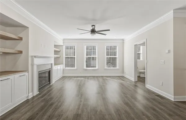 an empty room with wooden floor fireplace and windows