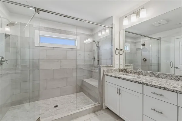 a bathroom with a granite countertop sink a mirror a glass door shower and vanity