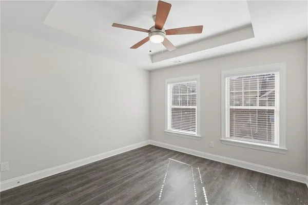 an empty room with wooden floor fan and windows