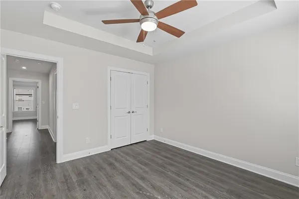 an empty room with wooden floor a ceiling fan and closet