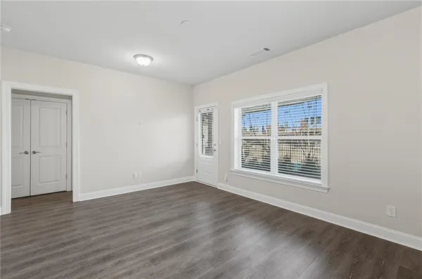 a view of an empty room with wooden floor and windows