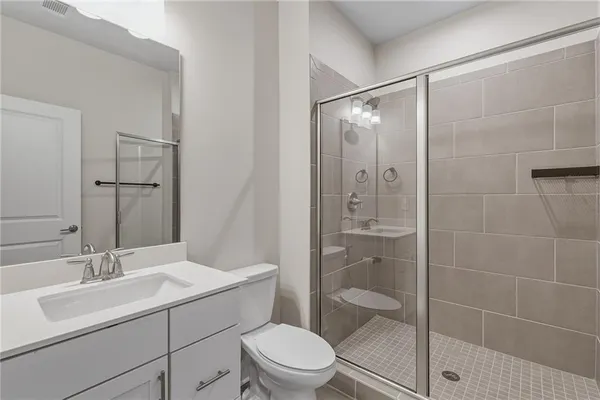 a bathroom with a shower sink vanity mirror and toilet