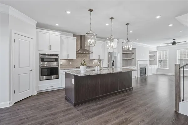 a large kitchen with stainless steel appliances kitchen island granite countertop a large island a stove a refrigerator a sink and a fireplace with wooden floor