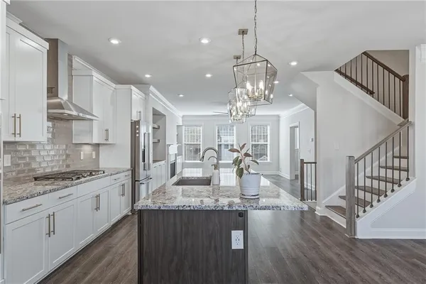 a large kitchen with granite countertop a large island in the center and stainless steel appliances