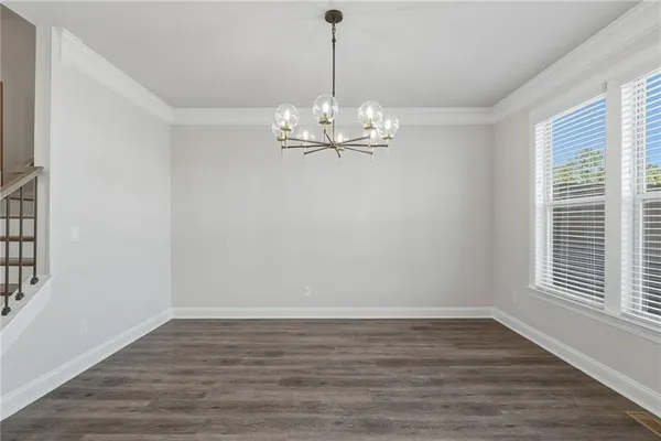 a view of a room with wooden floor chandelier and windows