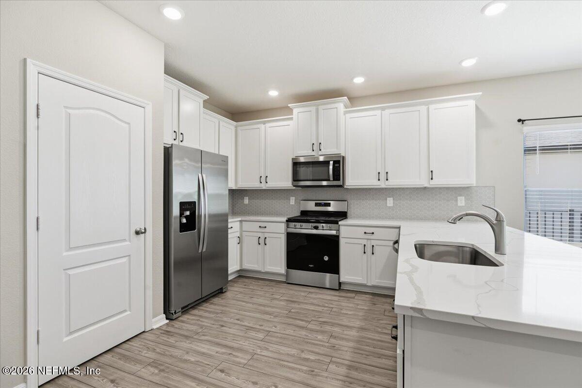 51 Tree Frog Way St. Augustine, FL 32095 - Photo 7 of 21 a kitchen with white cabinets and stainless steel appliances