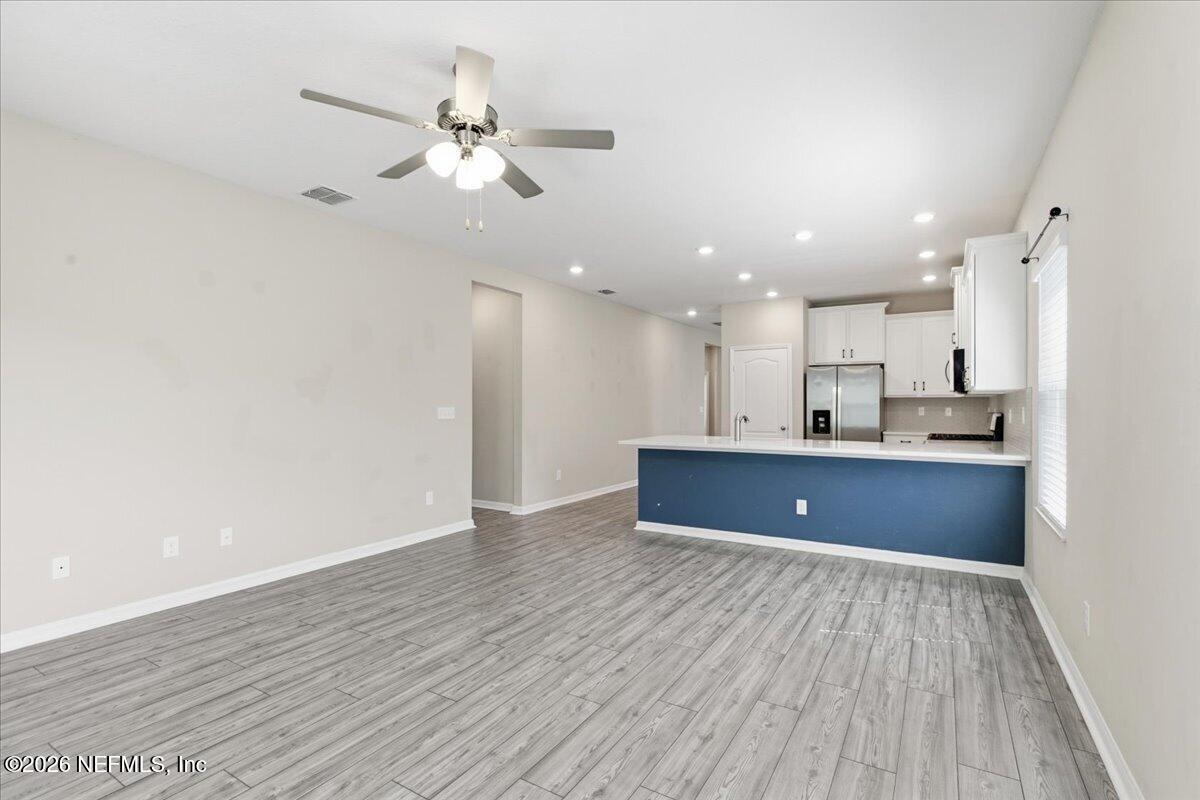 51 Tree Frog Way St. Augustine, FL 32095 - Photo 9 of 21 a view of an empty room and kitchen with wooden floor