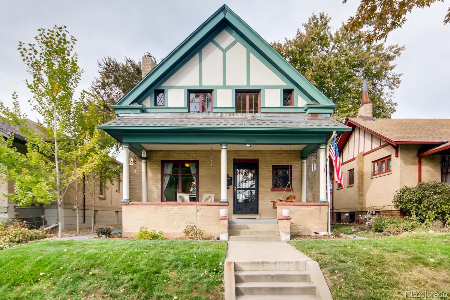 a view of a white house with large windows and a yard with plants
