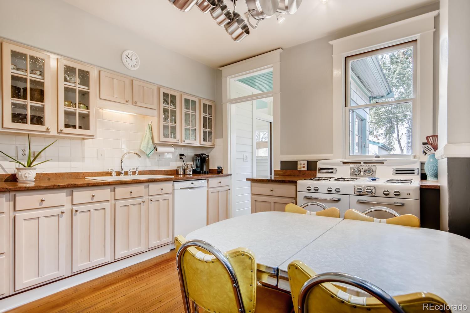 3345 Raleigh Street Denver, CO 80212 - Photo 11 of 27 a kitchen with stainless steel appliances granite countertop a stove a sink dishwasher and white cabinets with wooden floor