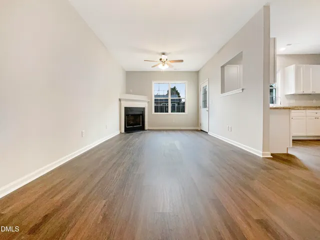 an empty room with wooden floor a ceiling fan and windows