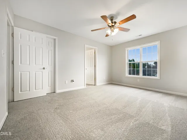 a view of an empty room with a ceiling fan and window