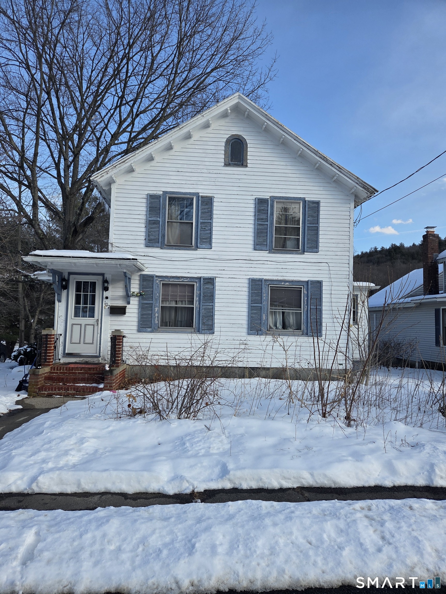 a view of a white house with large windows next to a yard