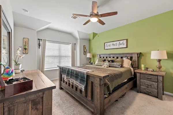 a bedroom with a bed a dresser and potted plant