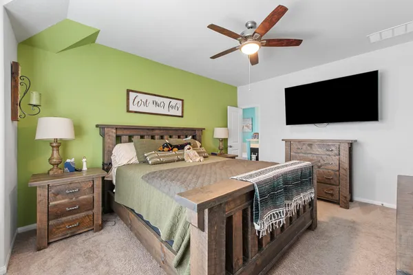 a spacious bedroom with a bed and a flat screen tv