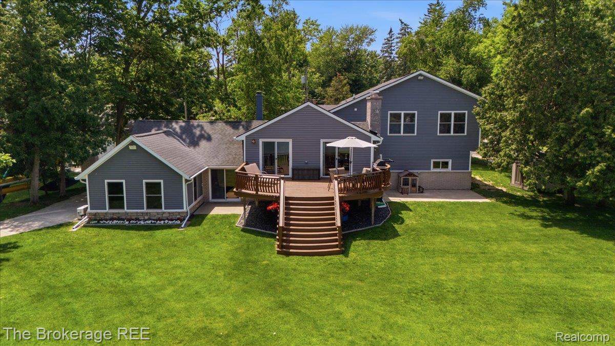 261 Reymont Road Waterford, MI 48327 - Photo 31 of 49 Expansive rear exterior featuring a multi-level wood-finish deck with integrated staircase, a spacious green lawn, and mature perimeter trees