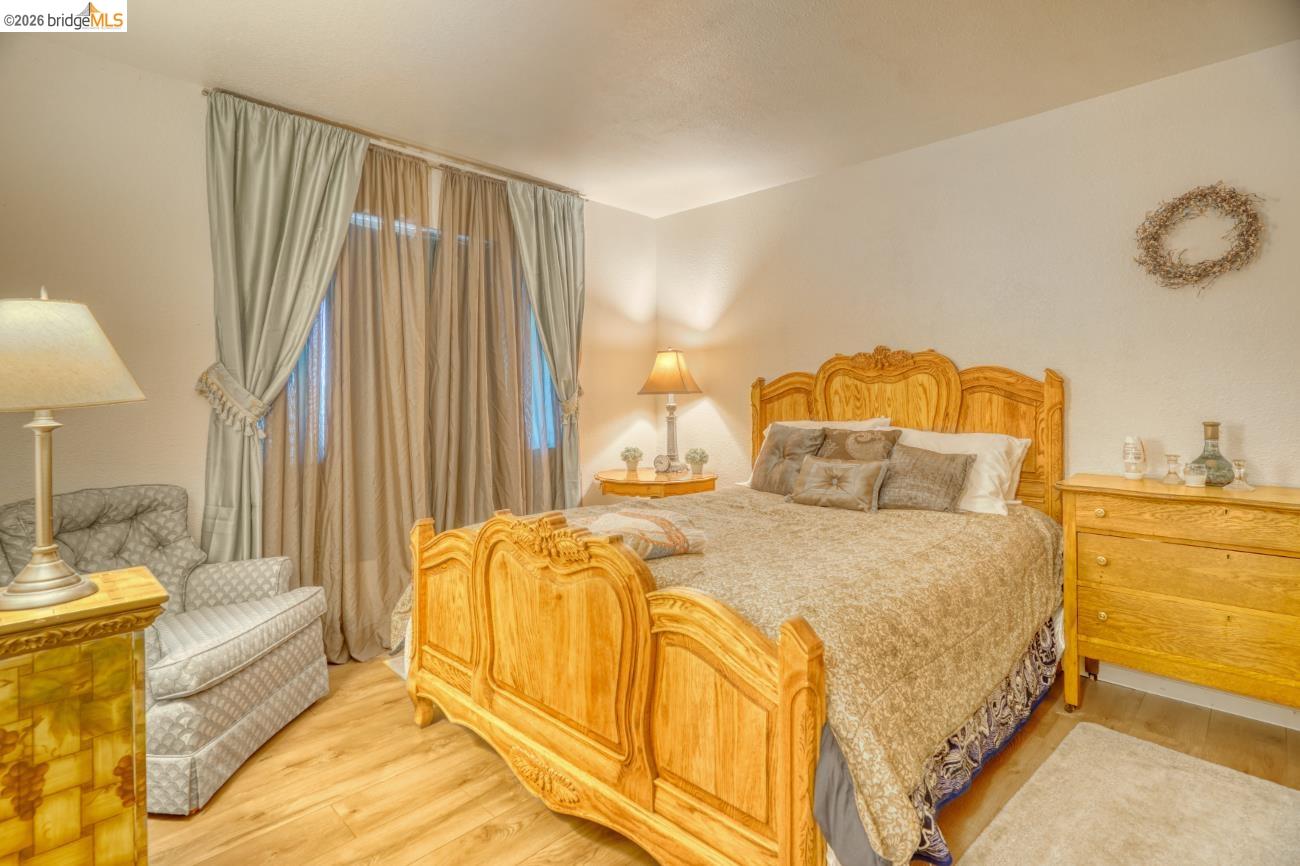 19215 Ferretti Road Groveland, CA 95321 - Photo 24 of 40 Bedroom featuring wood-finish flooring, light-toned walls, and a large window with drapes and sheer curtains