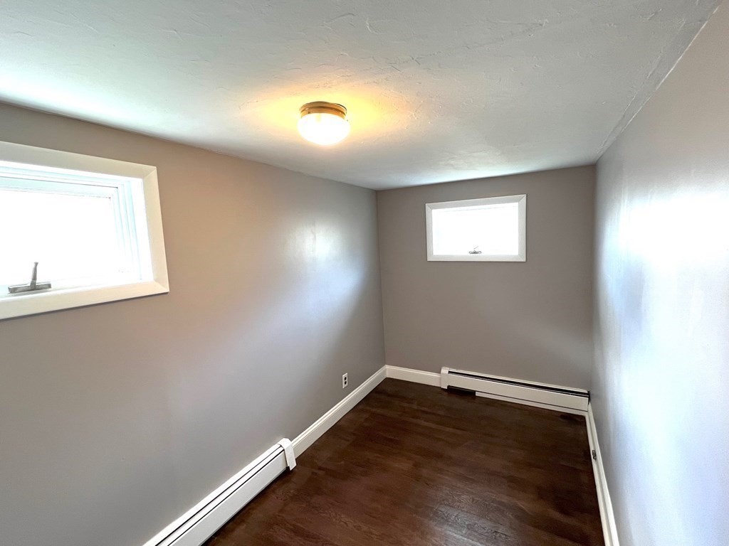 150 Locust Street, Unit 1 Winthrop, MA 02152 - Photo 8 of 11 an empty room with wooden floor and windows